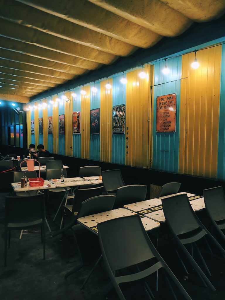 a dining area with tables and chairs in front of a yellow and blue wall
